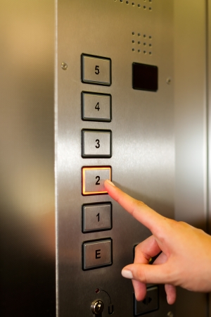 11529230 - woman in elevator or lift is pressing the button to get into the right floor; only hand to be seen - close-up